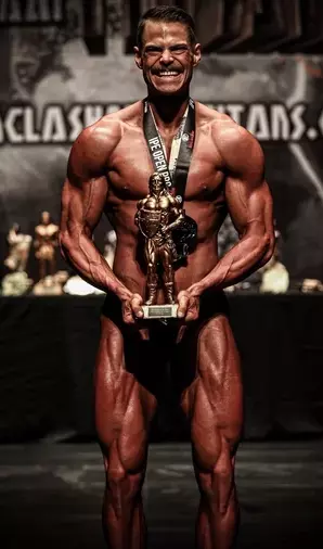Machete holding the winning prize at the Clash of the Titans Bodybuilding Show - Athlete